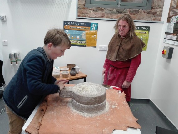 young boy hand milling on old style millstones